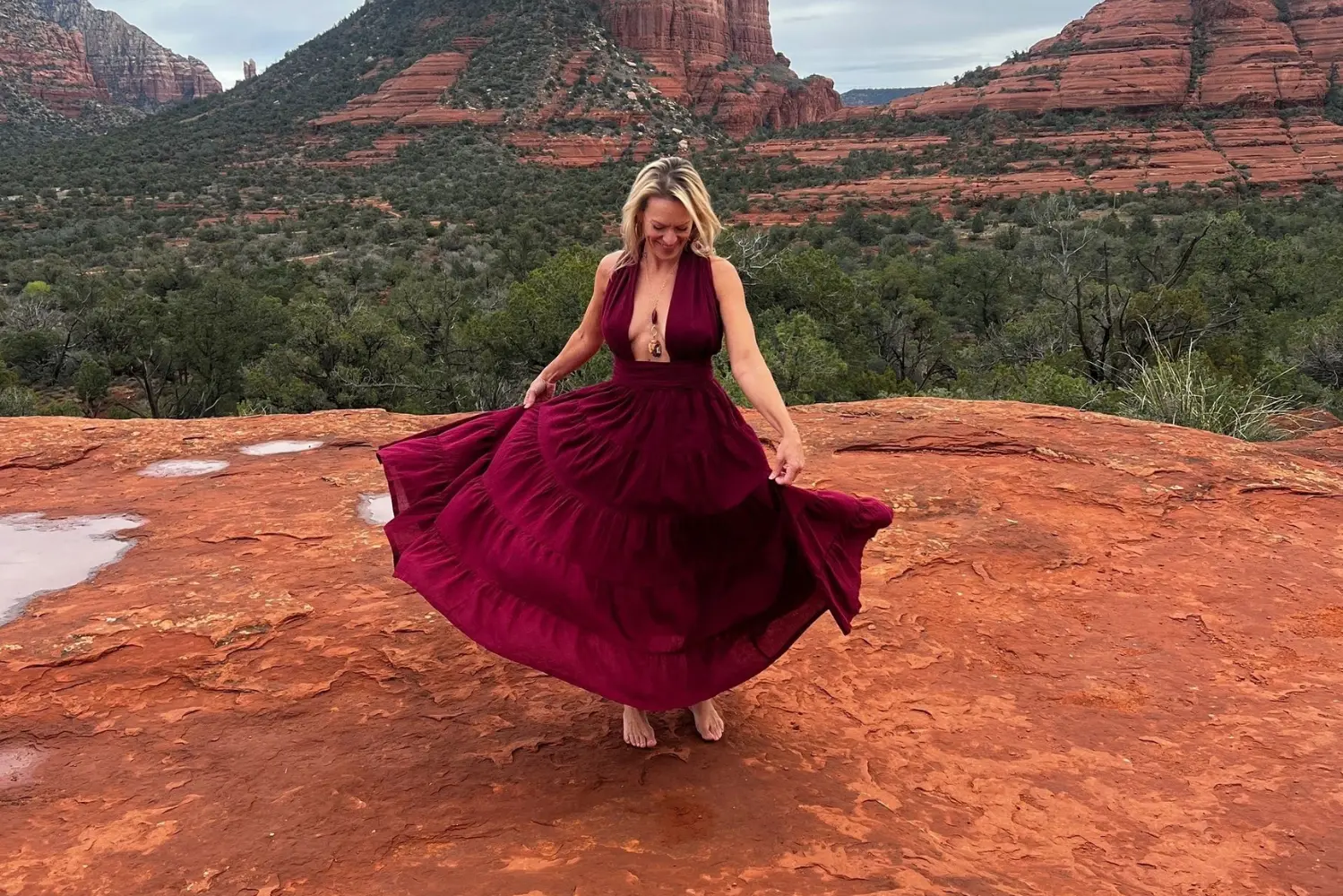 Woman twirling in red dress on rocks