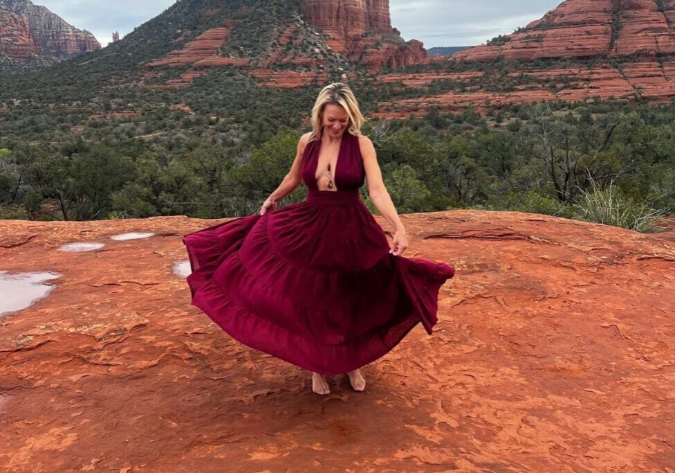 Woman twirling in red dress on rocks